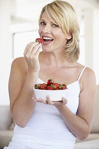 Mid Adult Woman Eating A Bowl Of Strawberries