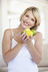 Mid Adult Woman Holding Fresh Fruit And Smiling At The Camera