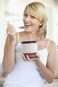 Mid Adult Woman Eating Chocolate Ice-Cream And Smiling At The Camera