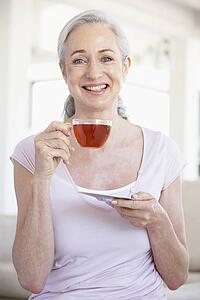 Senior Woman Holding Tea And Smiling At The Camera