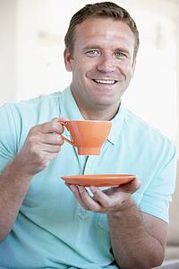 Mid Adult Man Holding Orange Mug And Smiling At The Camera