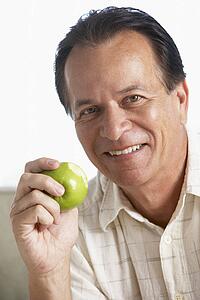Middle Aged Man Eating Green Apple And Smiling At The Camera
