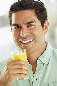 Mid Adult Man Holding A Glass Of Fresh Orange Juice, Smiling At The Camera