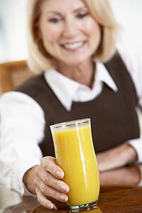 Senior Woman Drinking A Glass Of Fresh Orange Juice