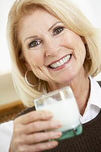 Senior Woman Holding A Glass Of Milk, Smiling At The Camera