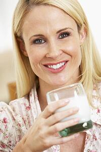 Mid Adult Woman Holding Glass Of Milk, Smiling At Camera