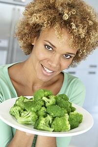 Mid Adult Woman Holding A Plate Of Broccoli, Smiling At The Camera
