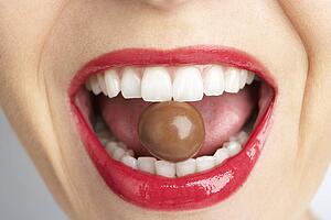 Close-Up Of Woman's Mouth Biting On Chocolate