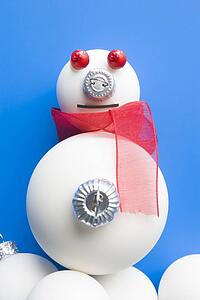 Snowman Made From Christmas Decorations Against Blue Background