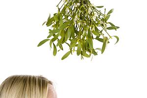 Woman Standing Under Bunch Of Mistletoe Against White Background