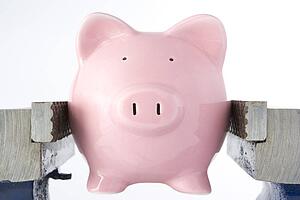 Piggy Bank In Jaws Of Vice Against White Background