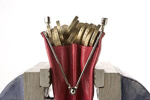 Ladies Purse Filled With Pound Coins Being Squeezed In Vice