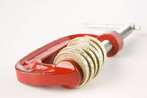Stack Of Pound Coins In Red Clamp On White Background