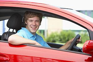 Teenage Boy Sitting In Car, Smiling At The Camera