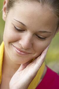 Portrait Of Teenage Girl Resting Head In Hands And Smiling