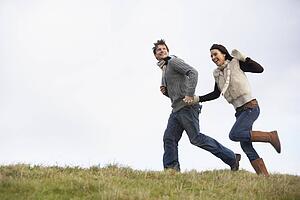 Couple Holding Hands And Running In The Park
