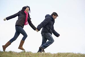 Couple Holding Hands And Running In The Park