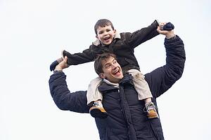 Father Carrying Son On His Shoulders