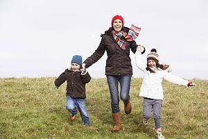 Mother And Her Children Running In The Park