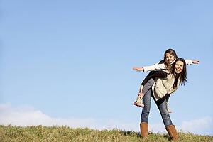 Mother Giving Her Daughter A Piggy Back Ride