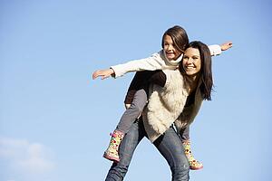 Mother Giving Her Daughter A Piggy Back Ride