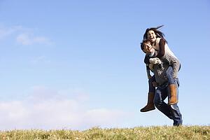 Man Giving His Wife A Piggy Back Ride In Park