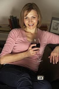 Woman Relaxing With Glass Of Wine Watching Television