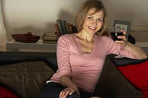 Woman Relaxing With Glass Of Wine Watching Television