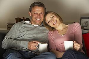 Couple With Coffee Mugs Watching Television