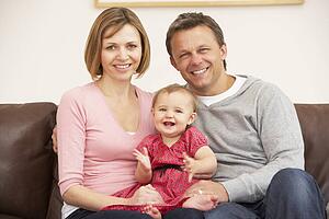 Parents And Baby Daughter On Sofa