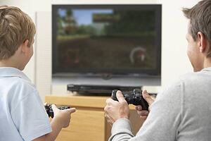 Father And Young Son Playing With Game Console