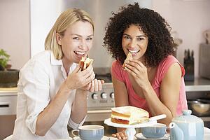 Female Friends Enjoying Tea And Cake At Home
