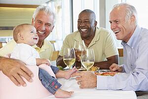 Man Showing His Baby Granddaughter To Friends At A Restaurant