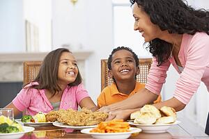 Mother Serving A Meal To Her Children At Home