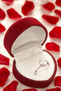Diamond Ring In Heart Shaped Box Surrounded By Rose Petals