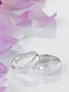 Silver Wedding Rings Resting Next To Flower Petals