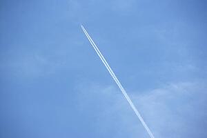 White Condensation Trail From A Jet As It Flies Across A Blue Sky