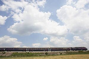 Passenger Train Moving Beneath A Clouded Sky