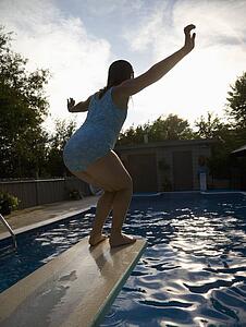 Girl on diving board over swimming pool
