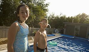 Girl and boy smiling by swimming pool