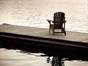 Lake of the Woods, Ontario, Canada; Empty deck chair on a pier next to a lake