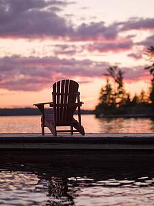 Lake of the Woods, Ontario, Canada; Empty deck chair on a pier next to a lake