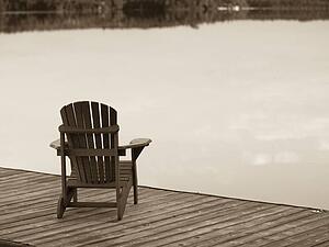 Lake of the Woods, Ontario, Canada; Empty deck chair on a pier next to a lake