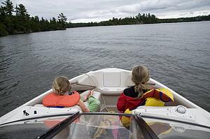 Lake of the Woods, Ontario, Canada; Girls sitting in front of boat