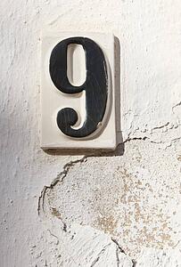 Ceramic number nine on whitewashed wall