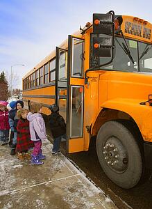 Elementary schoolchildren boarding school bus on a cold winter day in Edmonton Alberta Canada