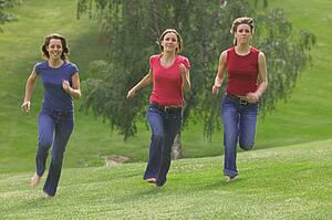 Three teen girls running in park