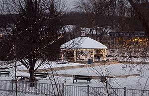 Christmas lights decorating a snow covered park and gazebo