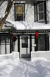 Christmas decorations hang outside on a snow covered house