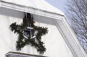 Christmas decorations hanging outside a snow covered house